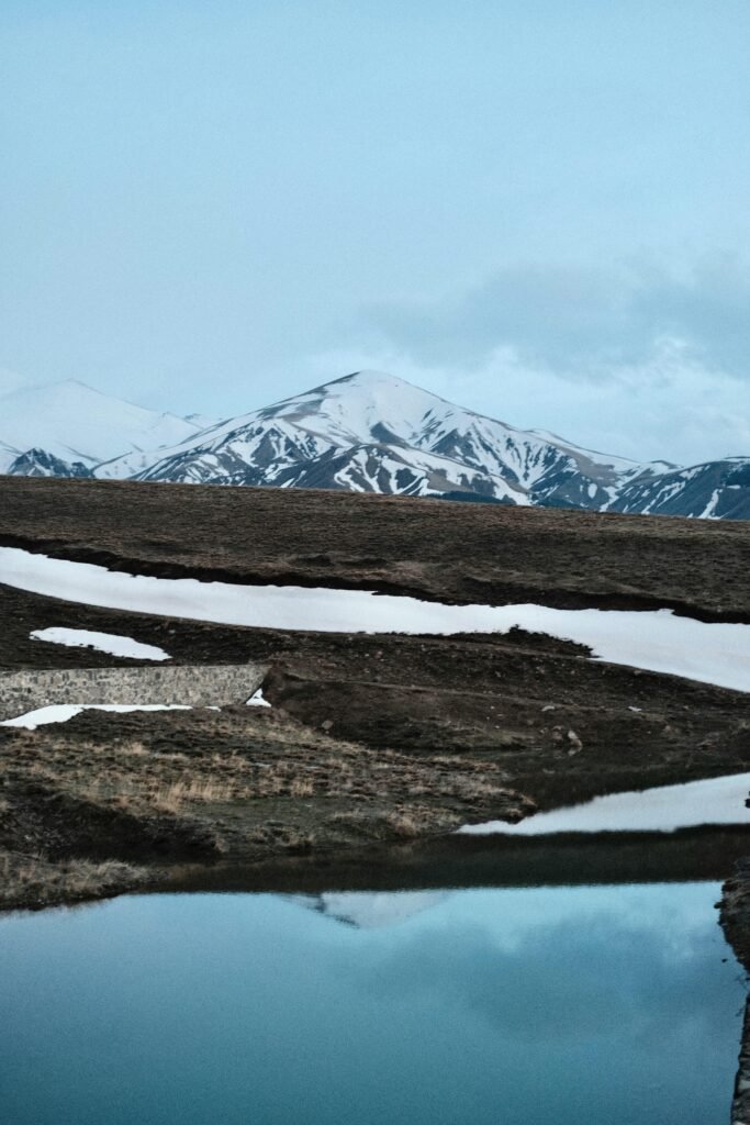 pexels-photo-31499866-31499866 A serene landscape featuring snow-capped mountains reflected in a calm lake under a clear sky.